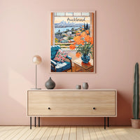 Scenic View of Auckland: Cozy Interior with Blue Armchair and Harbor Poster
